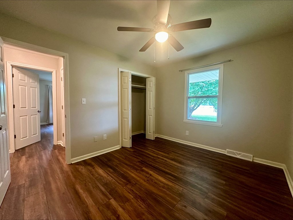 an empty living room with wood floors and a ceiling fan