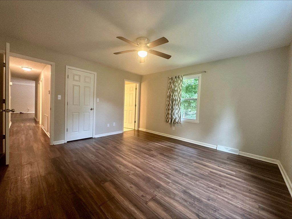 an empty living room with wood floors and a ceiling fan