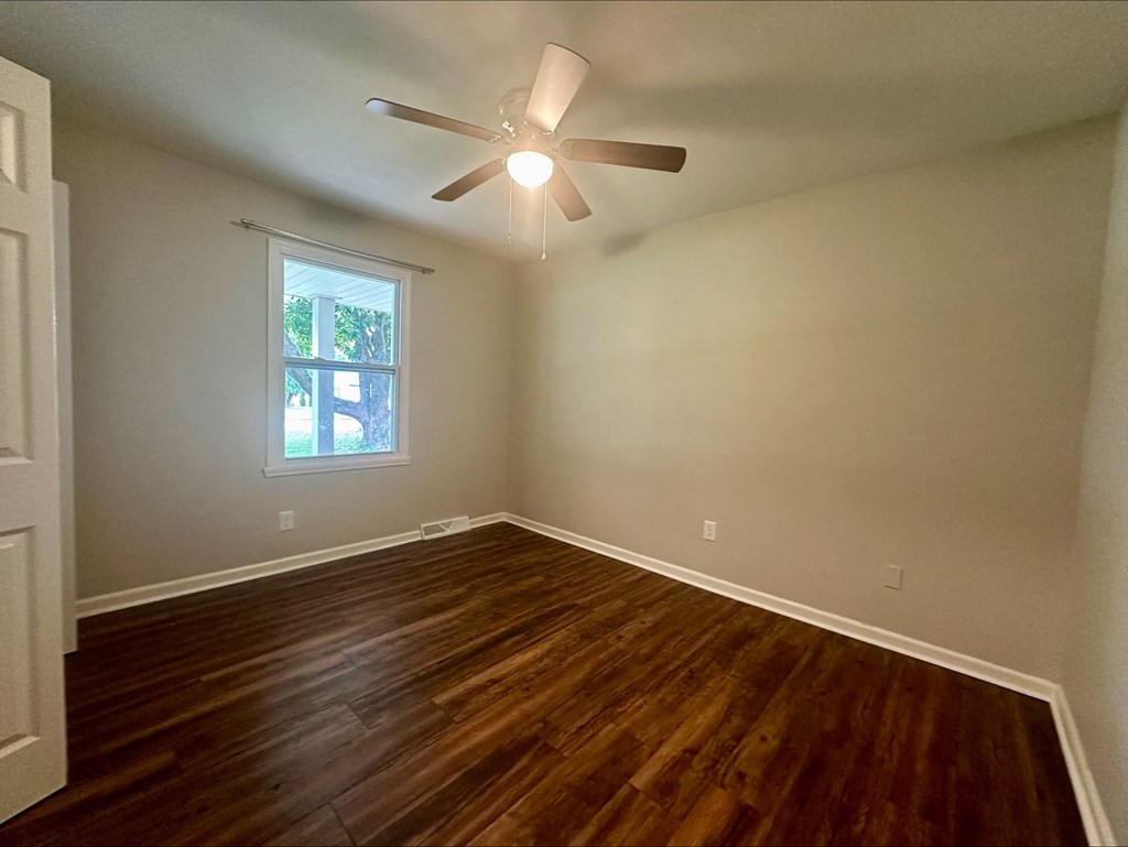 an empty living room with wood floors and a ceiling fan