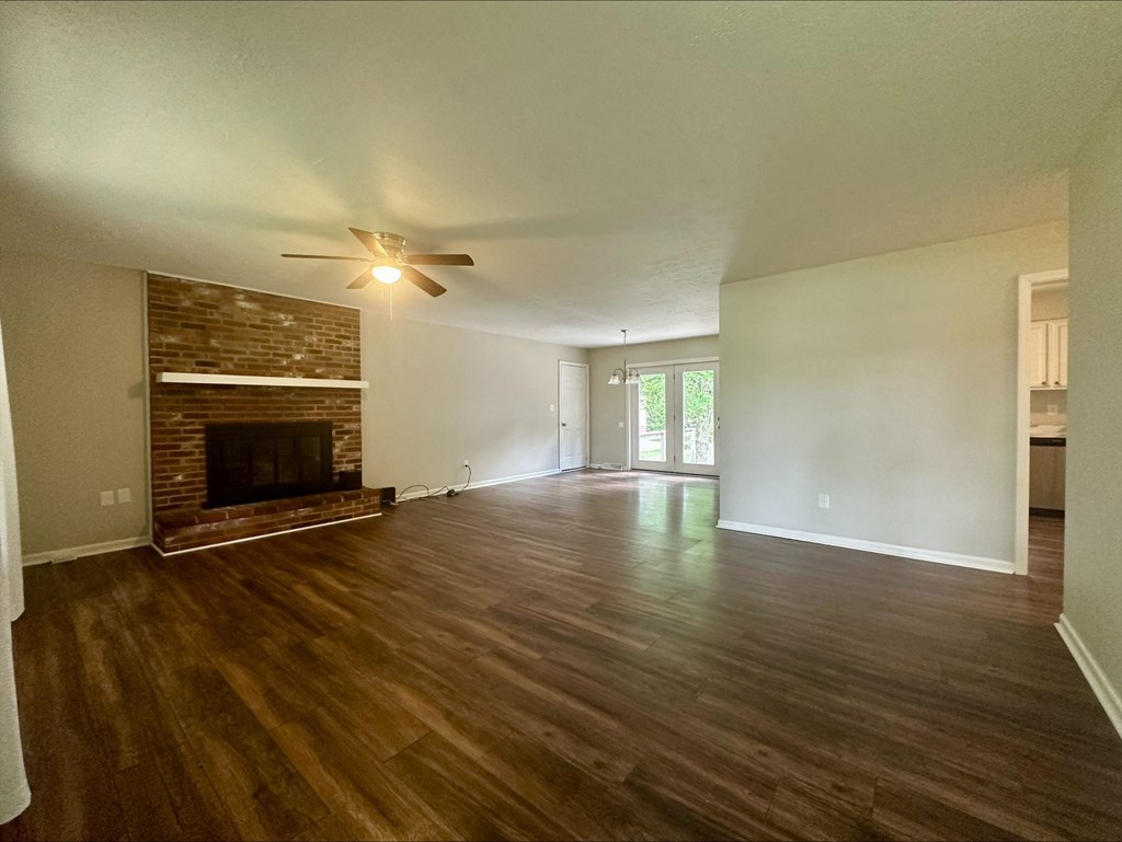 an empty living room with a fireplace and a ceiling fan