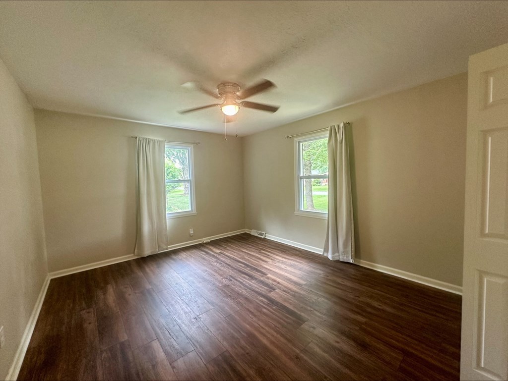 an empty living room with wood floors and a ceiling fan