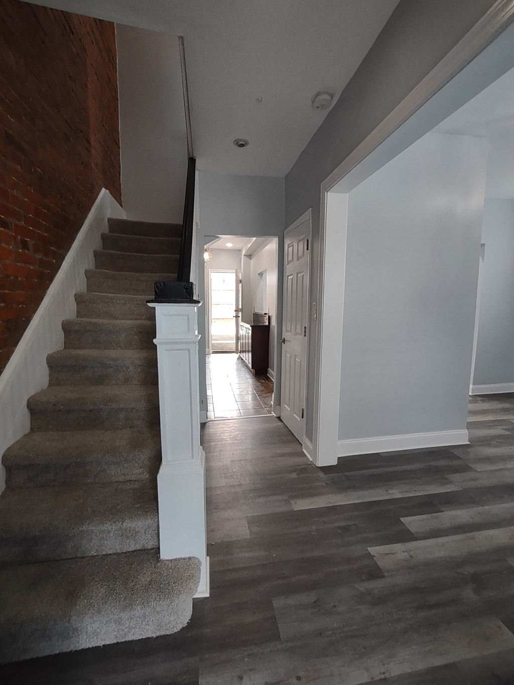 a view from the bottom of the stairs looking into the hallway and into the kitchen