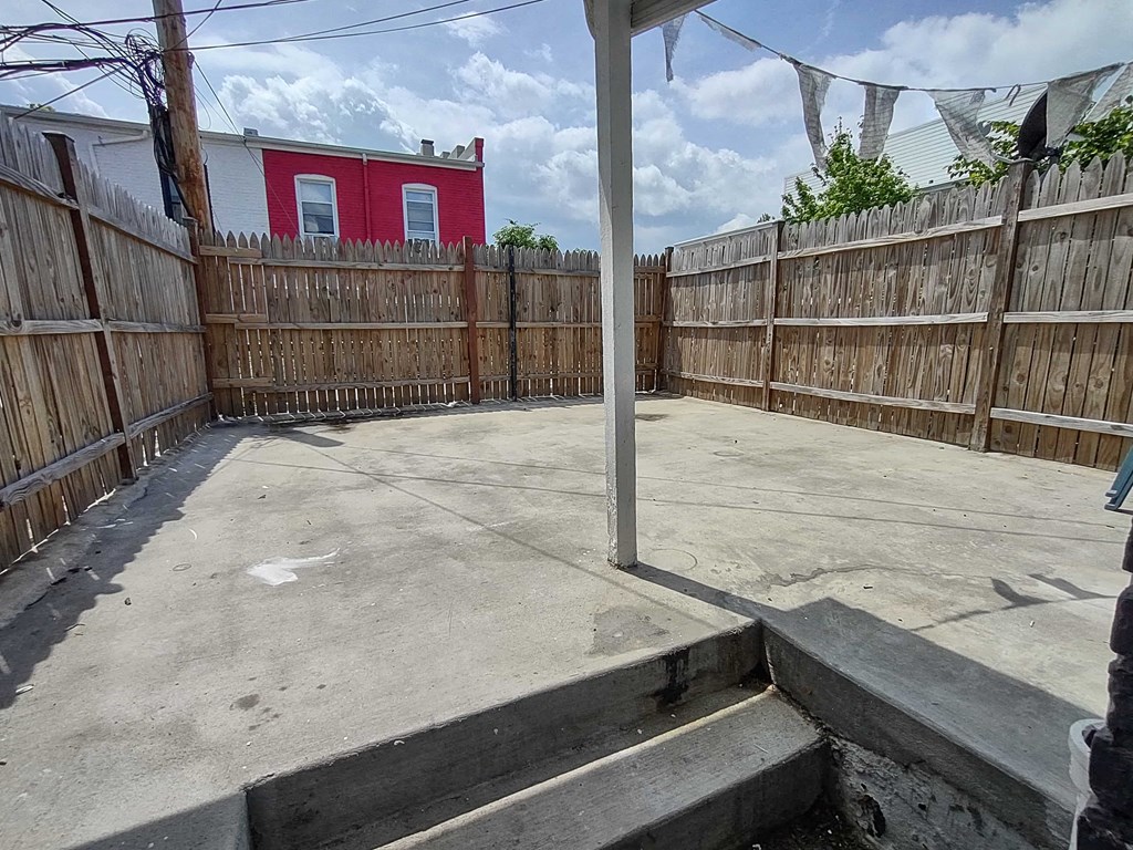 a yard with a wooden fence and a red house behind it