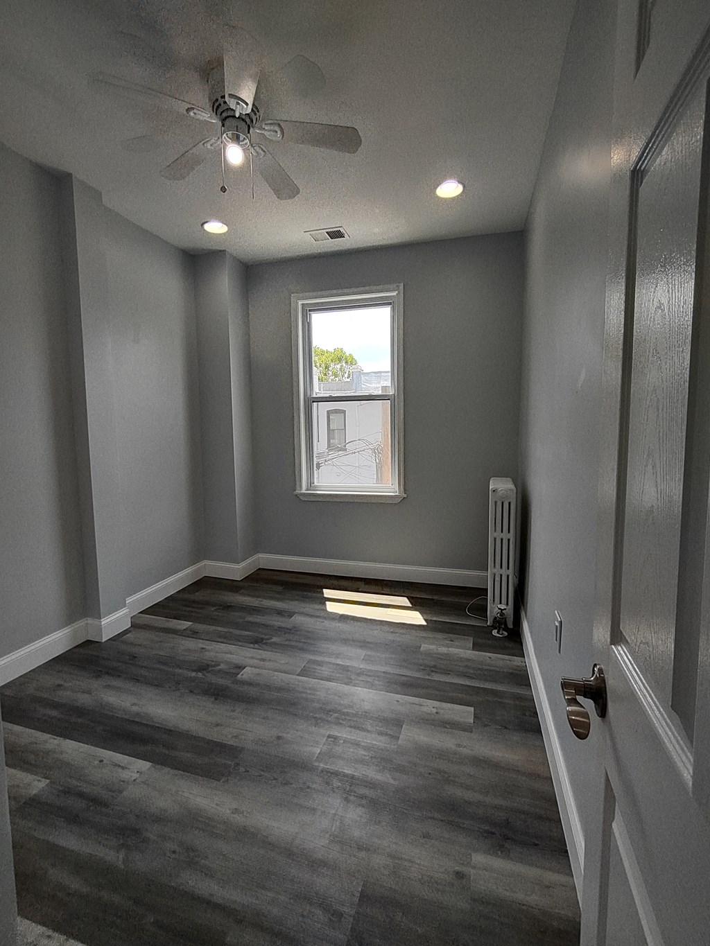 a empty room with a ceiling fan and a window