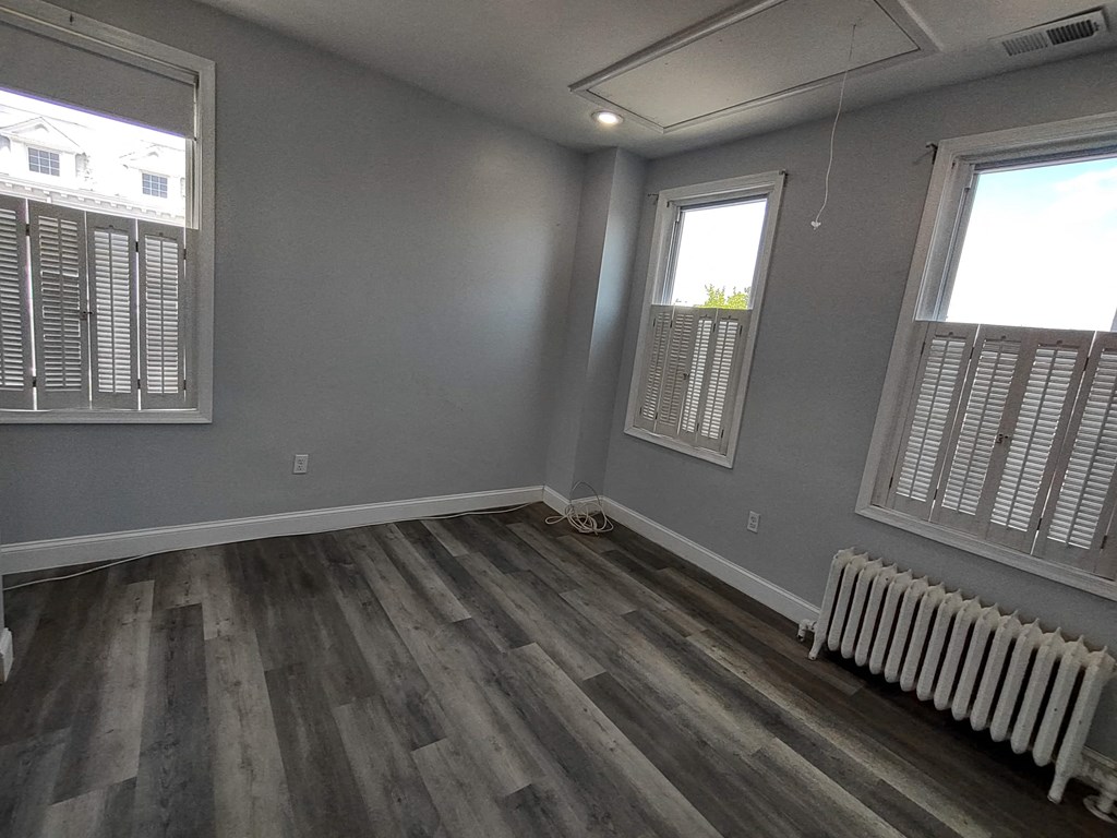 a living room with gray walls and wooden floors and a radiator