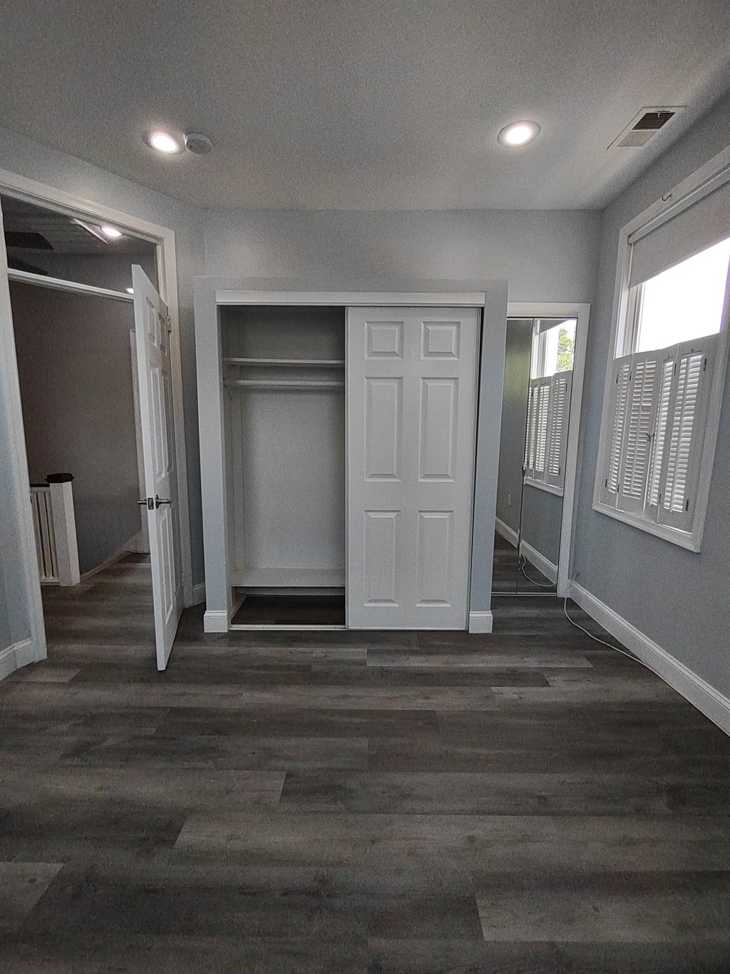 a living room with a white door and a hallway with a closet