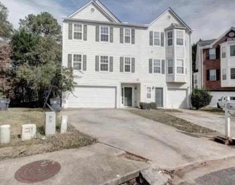 A white two-story house with a garage and a driveway.