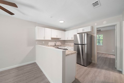 A kitchen with a stainless steel refrigerator and white cabinets.