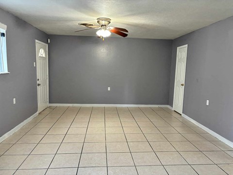 a empty living room with a ceiling fan and a tiled floor