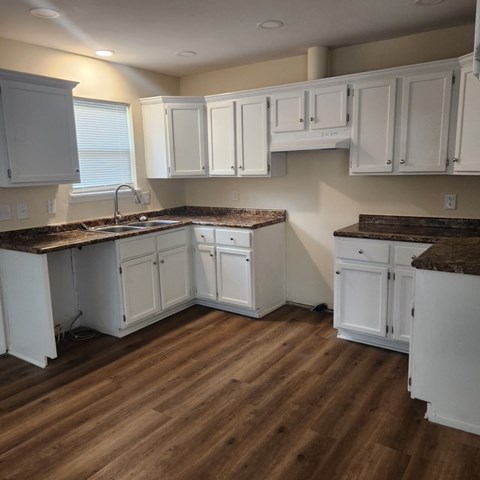 A kitchen with white cabinets and a brown countertop.