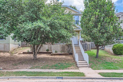 a house with stairs and trees in front of it