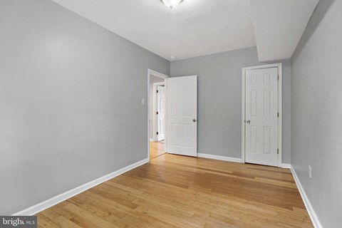 a living room with a hardwood floor and a door to a bedroom