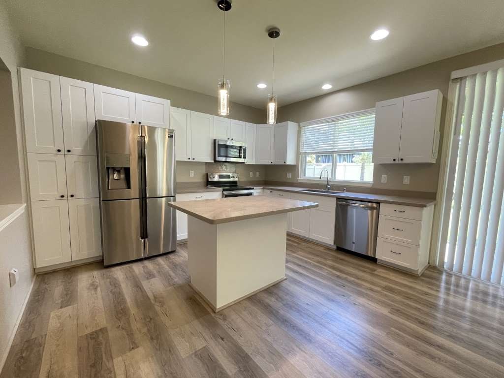 a kitchen with white cabinets and a stainless steel refrigerator
