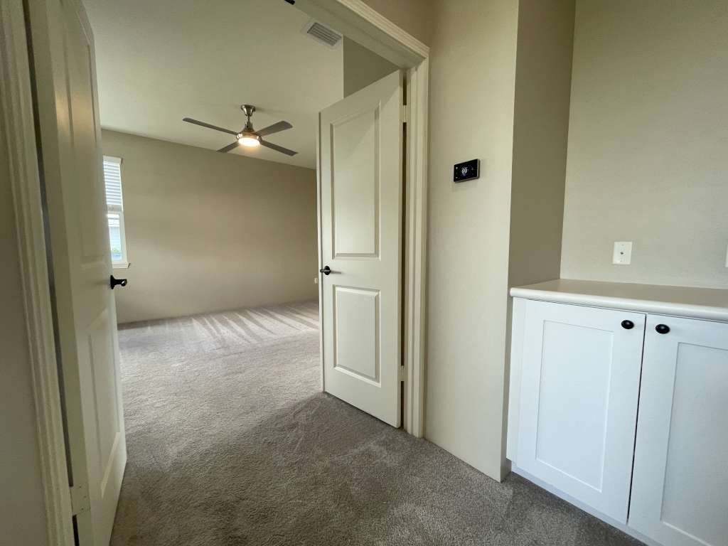 an empty living room with a ceiling fan and a closet