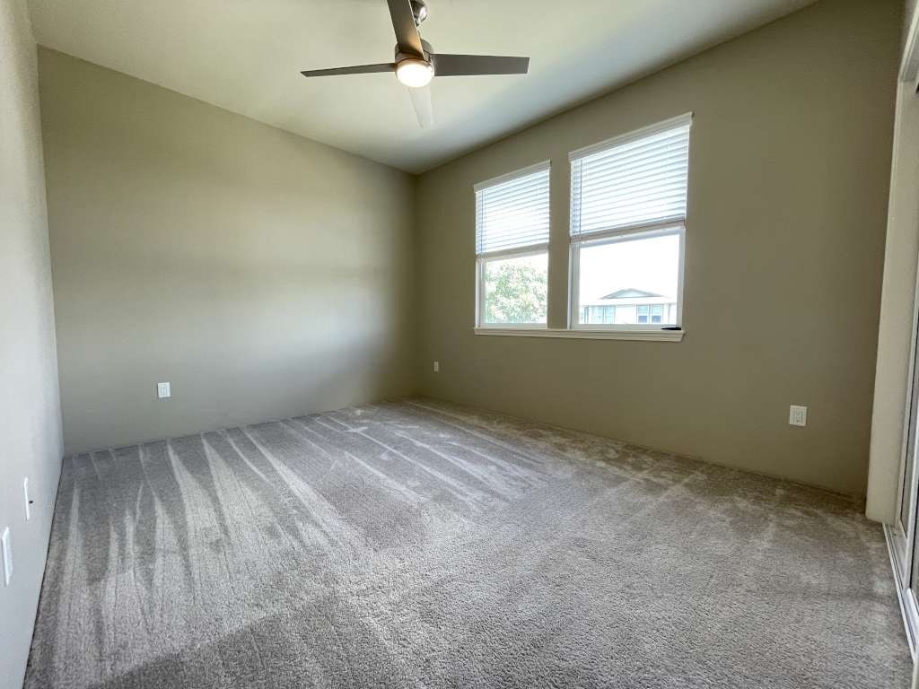an empty room with a ceiling fan and a window
