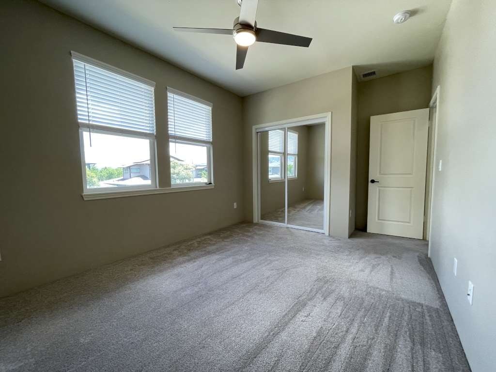 an empty living room with a ceiling fan and a window