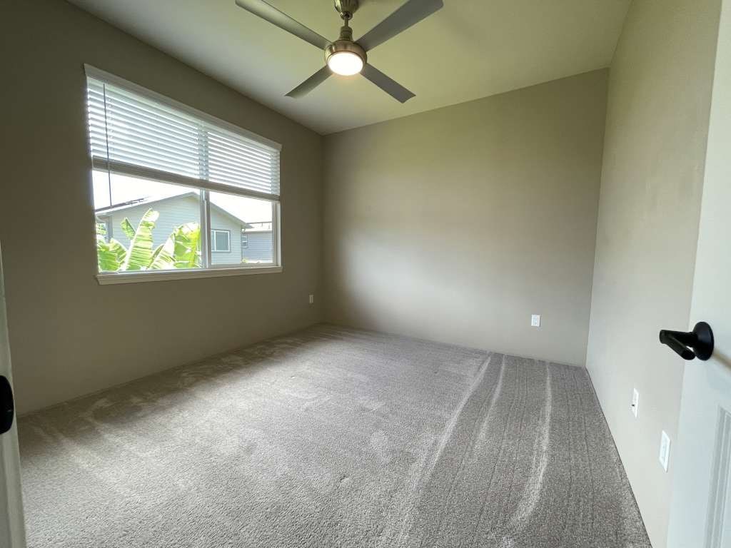 an empty room with a ceiling fan and a window