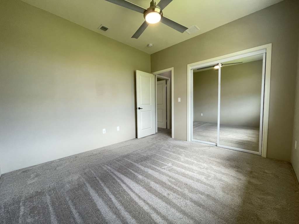 an empty living room with a ceiling fan