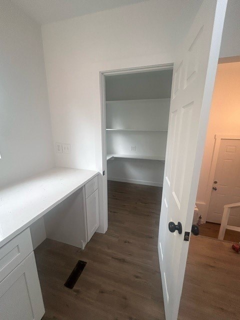 A white door is open to a room with a white counter and shelves.
