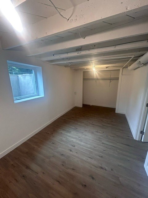 A room with wooden flooring and a window on the left side.