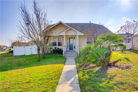 A house with a white picket fence and a tree in front.