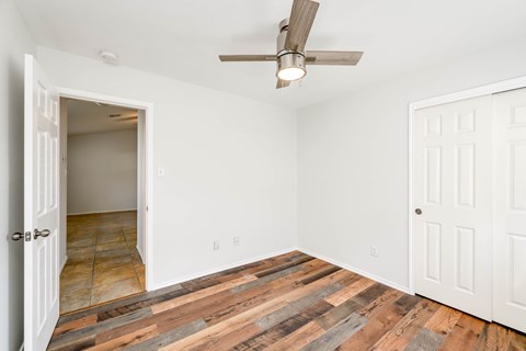 A room with a ceiling fan and wooden flooring.