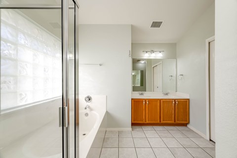 A white bathroom with a tub, sink, and mirror.