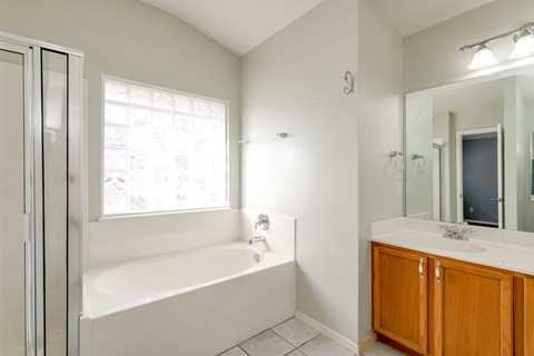 A white bathroom with a tub, sink, and mirror.