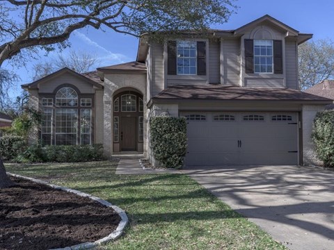A house with a brown door and a grey garage door.