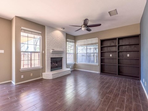 A living room with a fireplace and a ceiling fan.