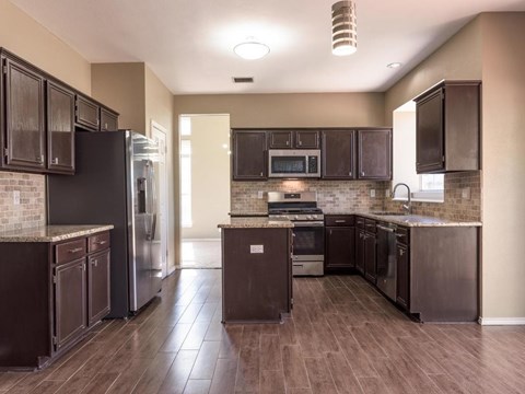 A kitchen with dark brown cabinets and a black refrigerator.