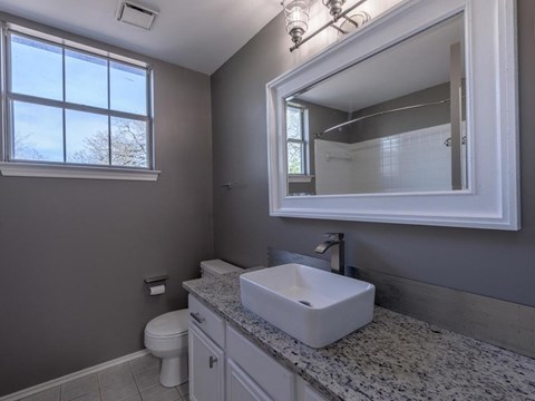 A bathroom with a toilet, sink, and mirror.