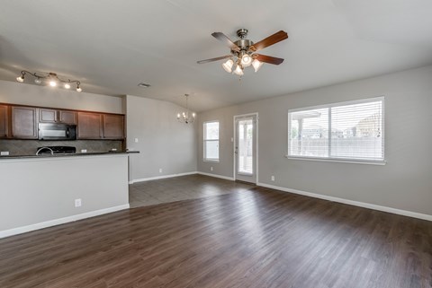 A spacious living room with a ceiling fan and hardwood floors.