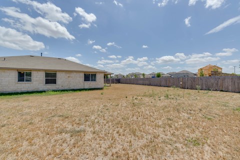 A large, open field with a building and a fence in the distance.
