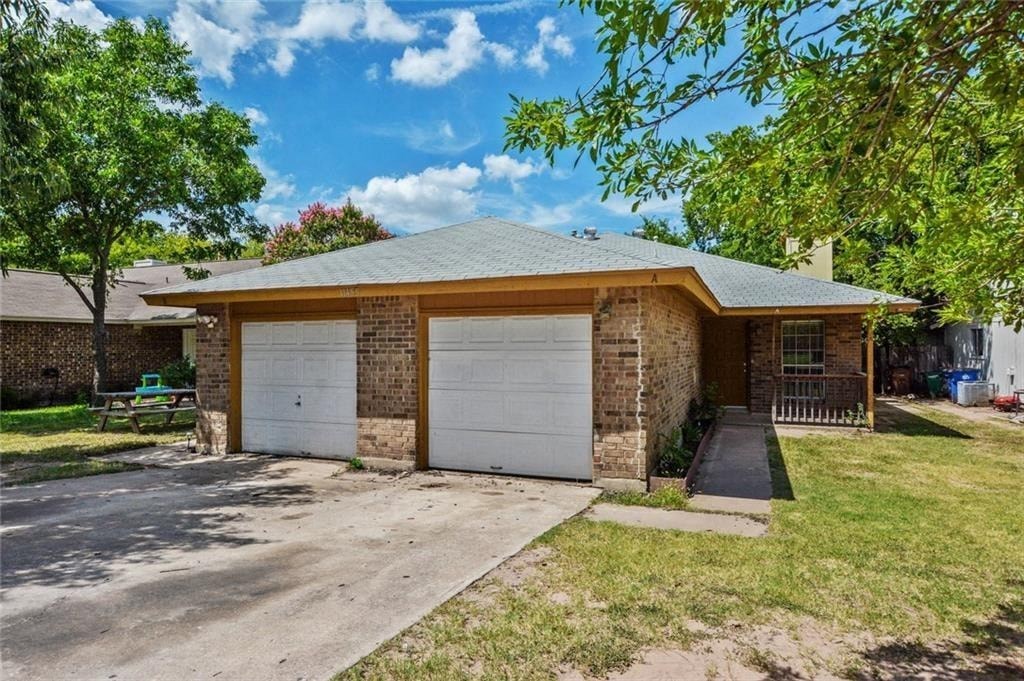 a brick house with two garage doors and a driveway