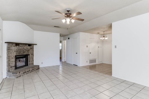 A spacious living room with a fireplace and a ceiling fan.