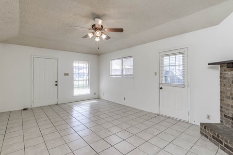 A spacious room with a ceiling fan and tiled flooring.
