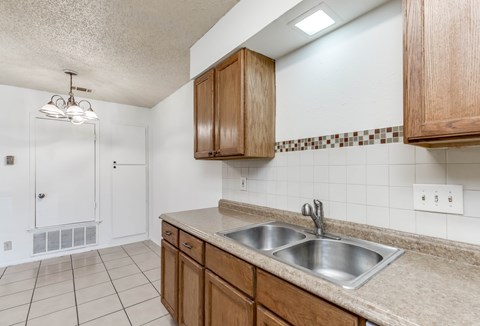 A kitchen with a sink and wooden cabinets.