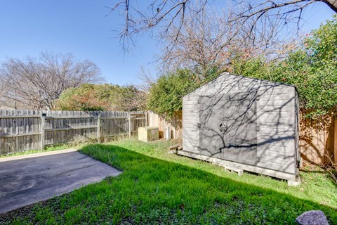 A shed sits in a grassy area next to a paved road.