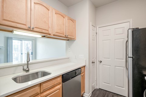 A kitchen with wooden cabinets and a black refrigerator.