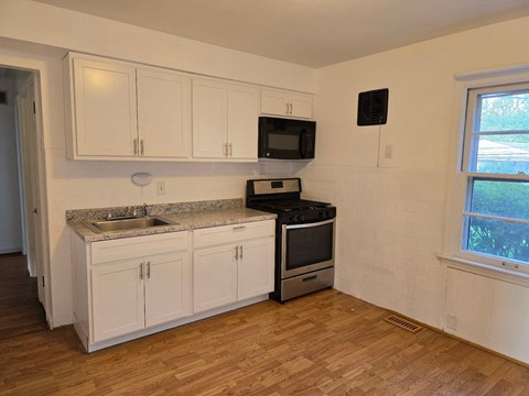 a kitchen with white cabinets and a stove and a sink