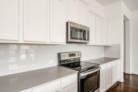 A kitchen with white cabinets and a black stove top oven.