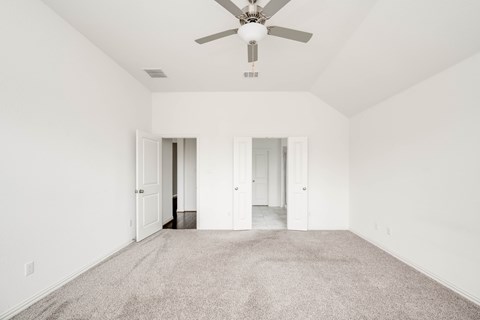 A spacious room with a ceiling fan and carpeted floor.