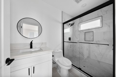 the bathroom has a large glass shower and a white sink and toilet