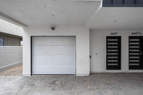a white house with a white garage door and two black doors