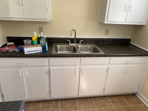 A kitchen with white cabinets and a black countertop.
