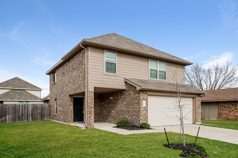 a tan and brown brick house with a garage door
