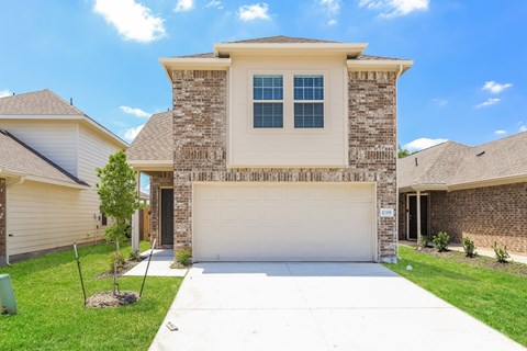 a beige house with a white driveway and a garage door