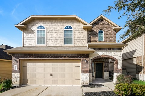a tan brick house with a white garage door