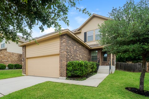 a tan and brown house with a sidewalk in front of it